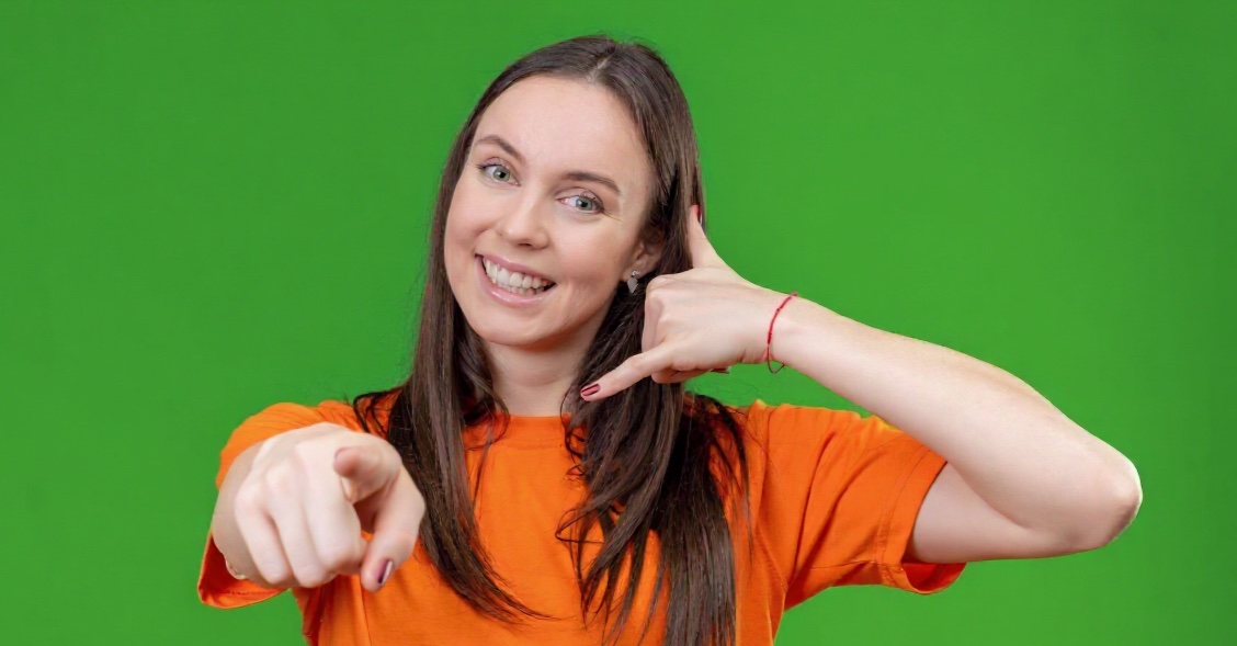 Junge Frau zeigt Telefonsymbol mit der Hand für einen Rückruf.